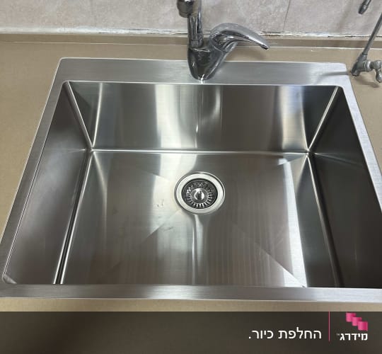 כיור נירוסטה עם ברז על משטח שיש